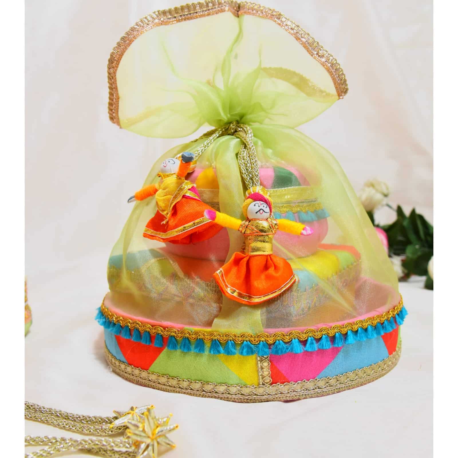 Round hamper basket for Holi with assorted goodies including water-soluble colors, pichkari, and balloon bunch.